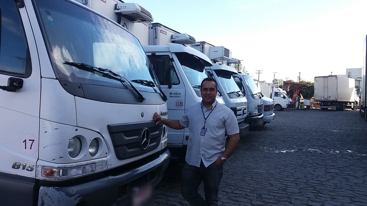 Controle de frota: Clauber, da Ideal Segurança, atendendo cliente no pátio da empresa ao lado dos veículos rastreados